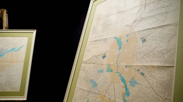 Maps on dark isolated background. Stock footage. Old paper maps of area are located on easels on black background in Museum