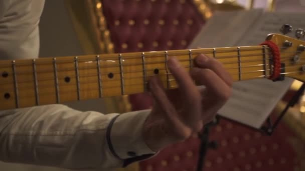 Close up of guitarrista mão tocando acordes de guitarra durante o concerto, arte e conceito de música. Imagens de stock. Músico masculino de camisa branca tocando guitarra elétrica com pescoço amarelo no evento . — Vídeo de Stock