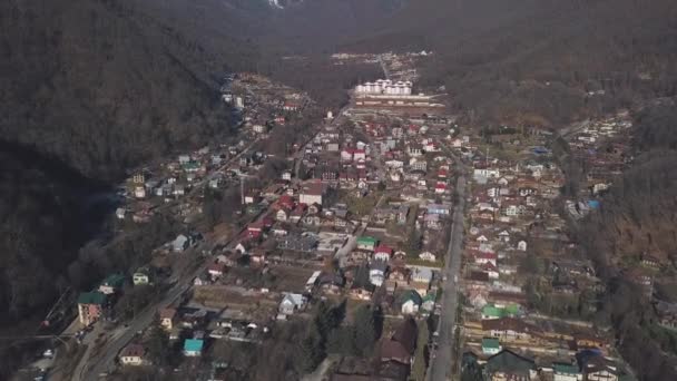 Vista aerea dell'inverno Austria villaggio nella valle vicino pittoresche montagne soleggiate Alp. Clip. Sorvolando le strade e le case della campagna circondate da alte colline boscose . — Video Stock