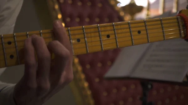 Close up of guitarrista mão tocando acordes de guitarra durante o concerto, arte e conceito de música. Imagens de stock. Músico masculino de camisa branca tocando guitarra elétrica com pescoço amarelo no evento . — Fotografia de Stock