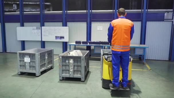 装载机上的工人在仓库中运送箱子.场景。站在装卸机上的工人控制它在工厂仓库运送货物箱 — 图库视频影像