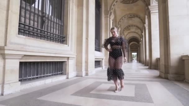 Mujer elegante en vestido largo y transparente y tacones altos caminando en el centro histórico de la ciudad europea. Acción. Elegante elegante sexy modelo de tamaño grande en la calle . — Vídeos de Stock