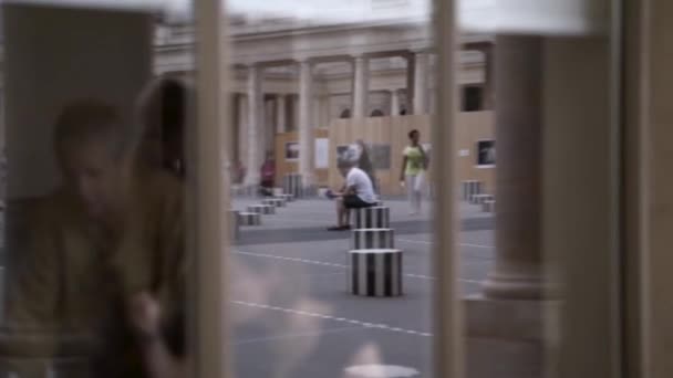 검은 옷을 입은 한 젊은 여자가 거리를 걷고 있는 모습이 떠오릅니다. 행동. 낡은 건물의 거울 유리 창문에 비친 세련 된 소녀의 모습. — 비디오