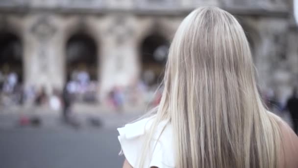 Camine por el centro histórico, hermosa chica, rubia con el pelo largo y recto contra un viejo edificio histórico con decoraciones. Acción. Concepto de viaje y turismo . — Vídeos de Stock