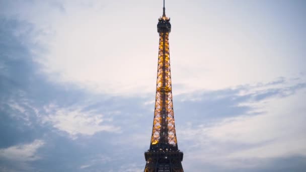 Torre Eiffel decorada por muchas lámparas brillantes y parpadeantes sobre fondo azul cielo nublado, Francia, París. Acción. La gente pasa tiempo en el prado verde cerca de la famosa vista . — Vídeos de Stock