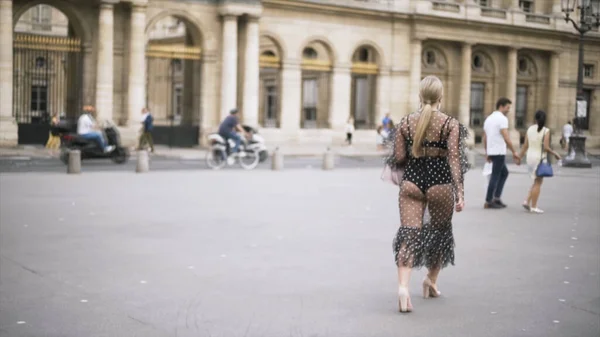 Jovem mulher bonita com cabelo loiro em frente a um grande edifício histórico, a França, viajando na Europa. Acção. Sexy senhora vestindo chiffon pontilhado vestido andando na rua . — Fotografia de Stock