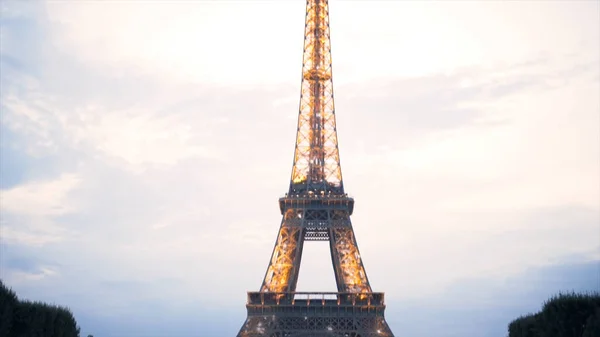 Torre Eiffel decorada por muchas lámparas brillantes y parpadeantes sobre fondo azul cielo nublado, Francia, París. Acción. La gente pasa tiempo en el prado verde cerca de la famosa vista . — Foto de Stock