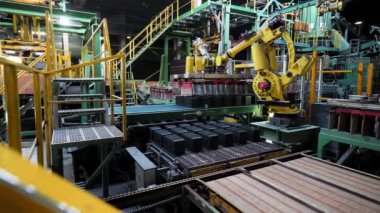 Plant for production of ceramic building blocks, professional technology. Stock footage. Working machinery and many rows of raw construction blocks on a conveyor belt.