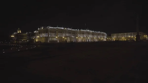 Vue de nuit de l'architecture pittoresque éclairée du centre-ville de Saint-Pétersbourg, majestueux palais d'hiver avec des gens qui se promènent. Motion. Célèbre bâtiment de l'Ermitage sur fond de ciel noir . — Photo