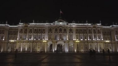 Saint Petersburg şehir merkezinin manzaralı, aydınlık mimarisi, görkemli Kış Sarayı. Etrafta insanlar geziniyor. Hareket. Kara gökyüzü arka planında ünlü Hermitage binası.