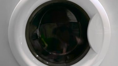 Çamaşır makinesinin kapısına yakın çekim ve içinde giysiler dönüyor. Kavram. Çamaşır makinesini kapat.