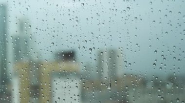 Yağmurlu bir günde camlı pencereyi kapatın. Bulanık şehrin arka planında büyük damlalar olsun. Stok görüntüleri. Dikey cam yüzeyde saydam su damlaları.