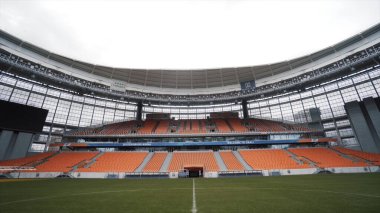 Ekaterinburg Arena, Rusya 'daki futbol stadyumunda boş koltuklar. Başla. Yeşil çimenli, kırmızı koltuklu panoramik futbol stadyumu, spor ve etkinlik konsepti.