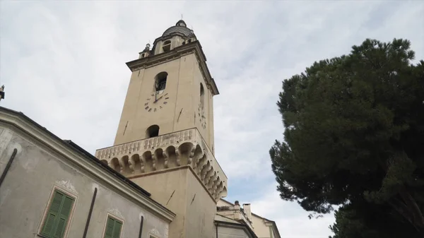 Bottom view of an ancient church with a tower and old clock on blue cloudy sky background, religion and architecture concept. Action. Chapel in the old town of a european city. — Stock Photo, Image