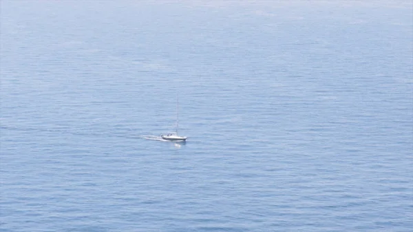 Aerial of white yacht in the Mediterranean sea with ripples. Action. Sailing ship moving slowly under the bright sun on a summer day. — Stock Photo, Image