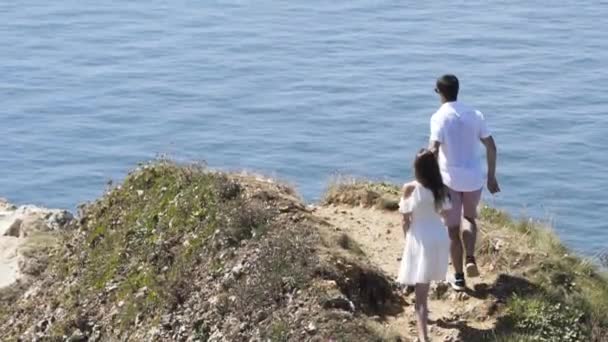 Vista de una pareja siguiendo un hermoso camino sobre el mar, el romance y el concepto de vacaciones. Acción. Hombre y mujer enamorados caminando junto al mar y tomados de la mano . — Vídeos de Stock