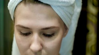 Güzel genç bir kadın banyoda yüzüne krem sürüyor. Kavram. Genç bir kadın için akşam ve sabah yüz bakımı. Güzel bir kadın yüzüne boksör gibi nemlendirici sürüyor.