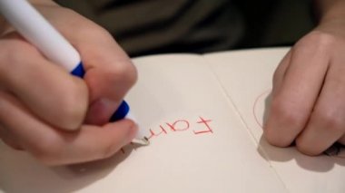 Defterde kalpleri olan çocuk notları. Kavram. Yüreğiyle çevrelenmiş çocuksu sözlere yakın çekim. Çocuk kelime ailesi yazdı ve kalbini çizdi.