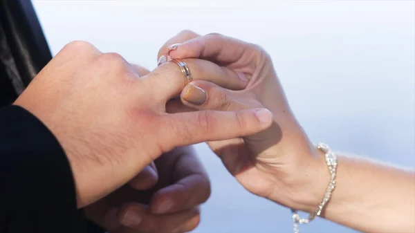 Großaufnahme der Hand einer Frau, die dem Mann einen goldenen Ehering an den Finger legt. Handeln. Tauschringe für die Trauung zwischen Braut und Bräutigam, Hände in Großaufnahme. — Stockfoto