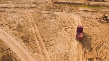 Taş ocağında çöp kamyonu sürüyor. Sahne. Taş ocağında tozlu yüzeyi olan çöl bölgesinden geçen çöp kamyonunun en üst görüntüsü. Taş ocağı operasyonları için ağır taşıma
