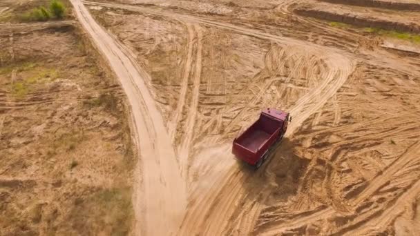 Dump truck driving on quarry area. Scene. Top view of dump truck driving through desert area with dusty surface at quarry. Heavy transport for quarry operations — Stock Video