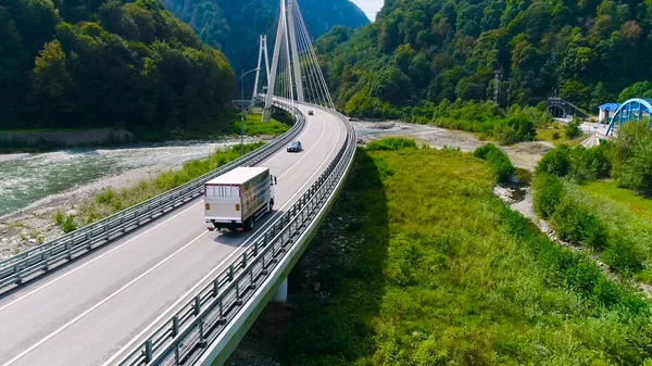 Camion traverse beau pont en été. Scène. Vue de dessus du camion transportant des choses conduisant à travers le pont sur fond de beau paysage forestier. Déplacement et réinstallation — Photo