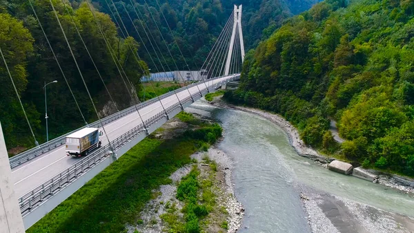 Camion attraversa bel ponte in estate. Scena. Vista dall'alto di camion che trasportano cose che attraversano il ponte sullo sfondo di un bellissimo paesaggio forestale. Viaggio e delocalizzazione — Foto Stock