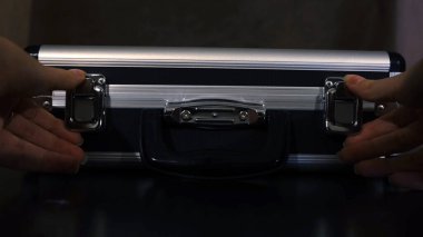 Sıra dışı eşyalarla dolu gizli bir bavul. Kavram. Siyah bavulu açan ve gizli eşyaları kontrol eden kadının yakın çekimi. Gizemli bavulda alışılmadık bir şey saklıyor.