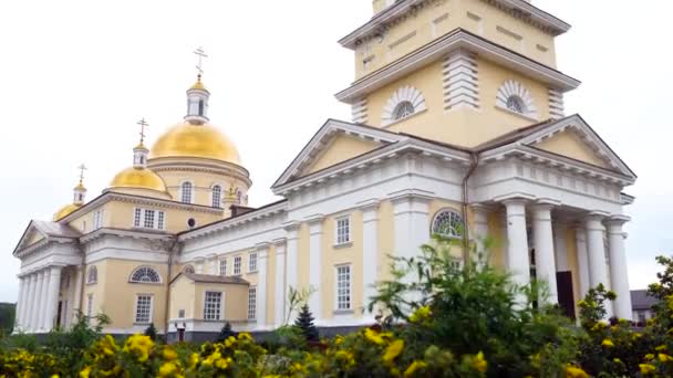 Красивый архитектурный фасад христианской церкви с золотыми куполами. Запись. Белые стены церкви с золотыми куполами на фоне облачного неба — стоковое видео
