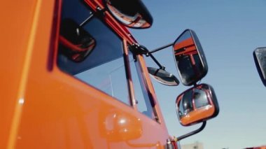 Yan aynayı kapat ve mavi açık gökyüzü arka planında kırmızı renkli kamyonun bir parçasını. Stok görüntüleri. Yeni kamyon detayları, inşaat konsepti.