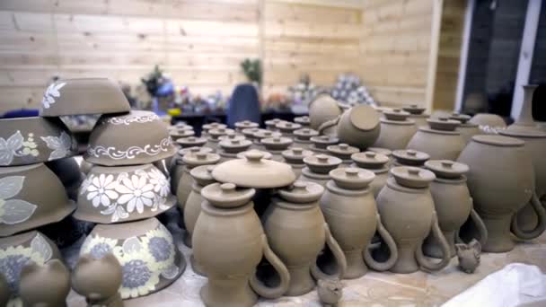Spousta domácí keramiky. Záběry ze skladu. Šedé hliněné nádobí s mnoha identickými sklenicemi a talíři na stole v dílně. Pottery workshop — Stock video