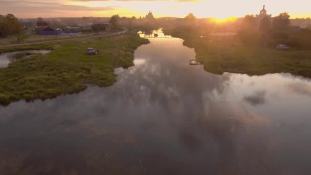 Piękne odbicie nieba w rzece przechodzącej przez wieś. Materiał filmowy. Widok z góry panorama rosyjskiego miasta w letni zachód słońca odzwierciedlone w rzece — Wideo stockowe