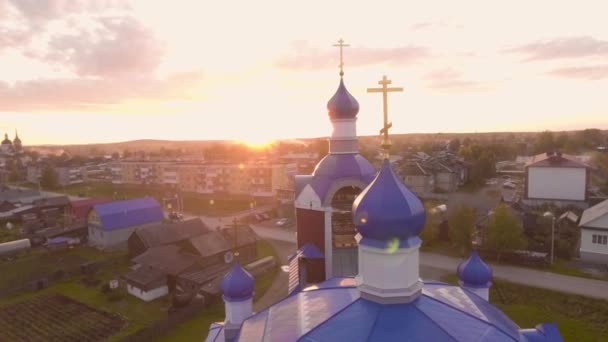 Russische Kerk in zonsondergang zonnestralen op de achtergrond van de stad. Voorraadbeelden. Top uitzicht op prachtige kleurrijke kerk verlicht door ondergaande zon in de Russische stad — Stockvideo