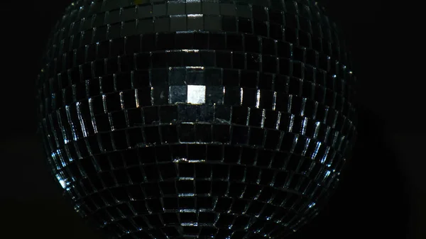 Крупним планом диско-куля на чорному тлі. Поняття. Диско-куля крутиться в темряві і відбиває світло. Красивий скляний диско-куля в темряві у відпустці — стокове фото