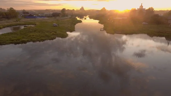 Красивое отражение неба в реке, проходящей через деревню. Запись. Вид сверху на панораму русского города на летний закат, отраженный в реке — стоковое фото