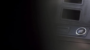 Modern bir arabanın içinde, sürücü düğmeye basarak motoru çalıştırıyor. Sahne. Lüks aracın içindeki çalıştırma düğmesine basan bir erkek eli..