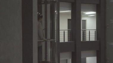 Asansörde bir kadın yükseliyor. Hisse. Kadın, modern cam asansörde çok katlı konut kompleksinde yükseliyor. Cam Asansör konut kompleksinin içinde