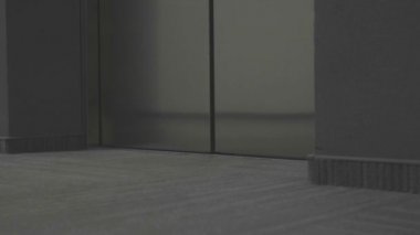Siyahlı adam asansörden çıkıyor. Hisse. Asansör kapıları açılıyor ve siyah elbiseli adam dışarı çıkıyor. Katil asansörden çıkar ve kurbanın kapısına gider.