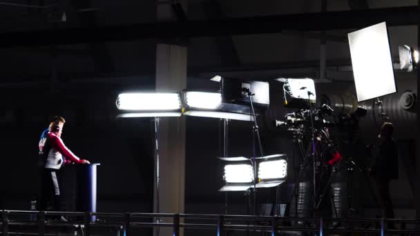 Tournage montre avec la lumière professionnelle et la caméra. Images d'archives. Les présentateurs se tiennent derrière le comptoir devant la caméra et les projecteurs pendant le tournage — Video