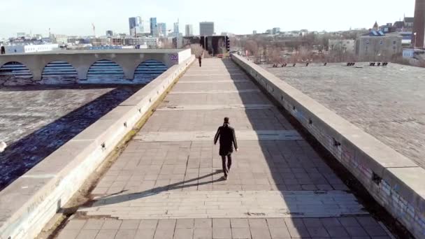 Top view of man walking on roof on background of city. Stock. Young man walks steeply in middle of road on background of city skyline on clear day — Stock Video