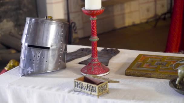 Casco de caballeros en la mesa. Acción. Los objetos medievales y el casco de los caballeros se encuentran sobre la mesa en el Museo histórico. Escenografía con accesorios de la vida medieval — Vídeo de stock