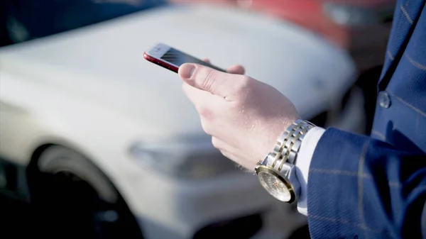 Gros plan d'un homme d'affaires pressant la clé d'une voiture. L'action. Homme d'affaires ouvre la voiture avec clé électronique et regarde le téléphone. Clé de voiture moderne pour l'ouvrir et le démarrer — Photo