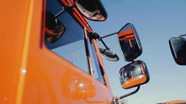 Gros plan du rétroviseur latéral et d'une partie du corps du camion de couleur rouge sur fond bleu ciel clair. Images d'archives. Nouveaux détails de camion, concept de construction . — Photo