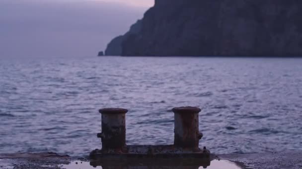 Zamknij betonową krawędź molo z widokiem na falowaną powierzchnię morza za nim. Postrzelony. Dramatyczny krajobraz wieczornego nieba, morza i wysokiej góry. — Wideo stockowe
