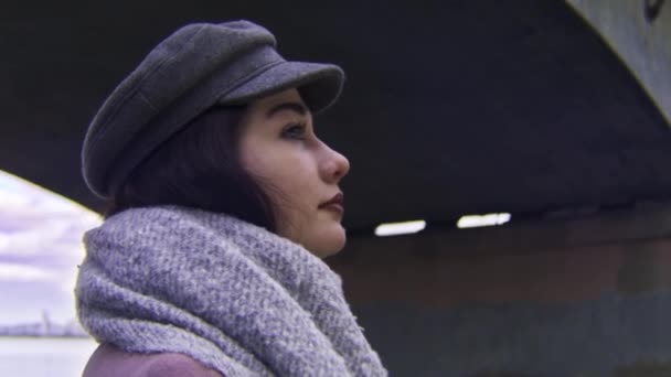 Vue latérale de la jeune femme brune avec un maquillage lumineux sous le pont de la ville. Images d'archives. Gros plan portrait de réfléchi anf triste fille regardant loin sur le bord de la rivière urbaine . — Video