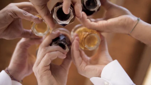 Vue du bas des verres clink avec de l'alcool. L'action. Gros plan des mains tenant des verres d'alcool l'une à l'autre. Verres clink festifs avec boissons alcoolisées — Photo