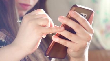 Telefonunu tutan ve not alan bir kızın yakın çekimi. Medya. Kız telefonda güneş ışığının arka planına stilus kullanarak notlar yazıyor. Stylus ile yaratıcı kişi telefonda notlar yazar ve yaratır.