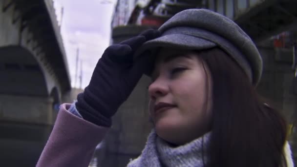 Young woman with dark hair looking thoughtful but sad. Stock footage. Portrait of a beautiful young woman in a pink coat and gloves, retro camera effect. — Stock Video