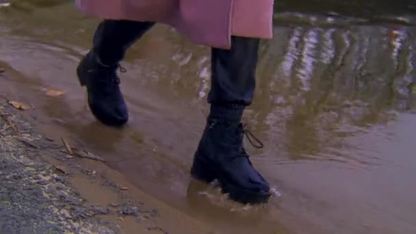 Közelkép női bőr fekete csizma sétál a homokos parton és a vízparton. Készletfelvétel. Részletek egy fiatal nőről, aki a folyó mellett sétál. — Stock videók