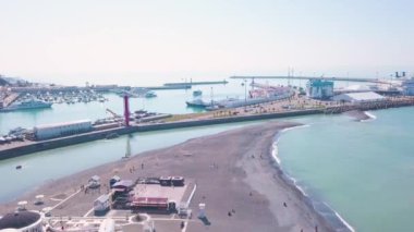 Yat körfezi olan bir pelerin. Şarjör. Yatlar için körfez ve turkuaz suyun arka planında deniz sanayisi olan güzel bir sahil. Yatları ve güneşli bir günde berrak turkuaz suları olan bir sahil.